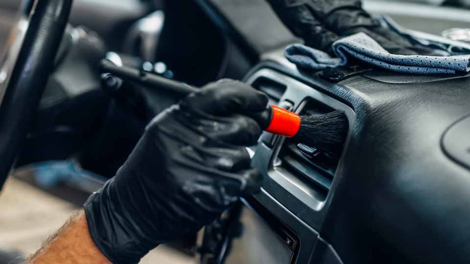 Ein Mechaniker reinigt das Armaturenbrett eines Autos in der Werkstatt